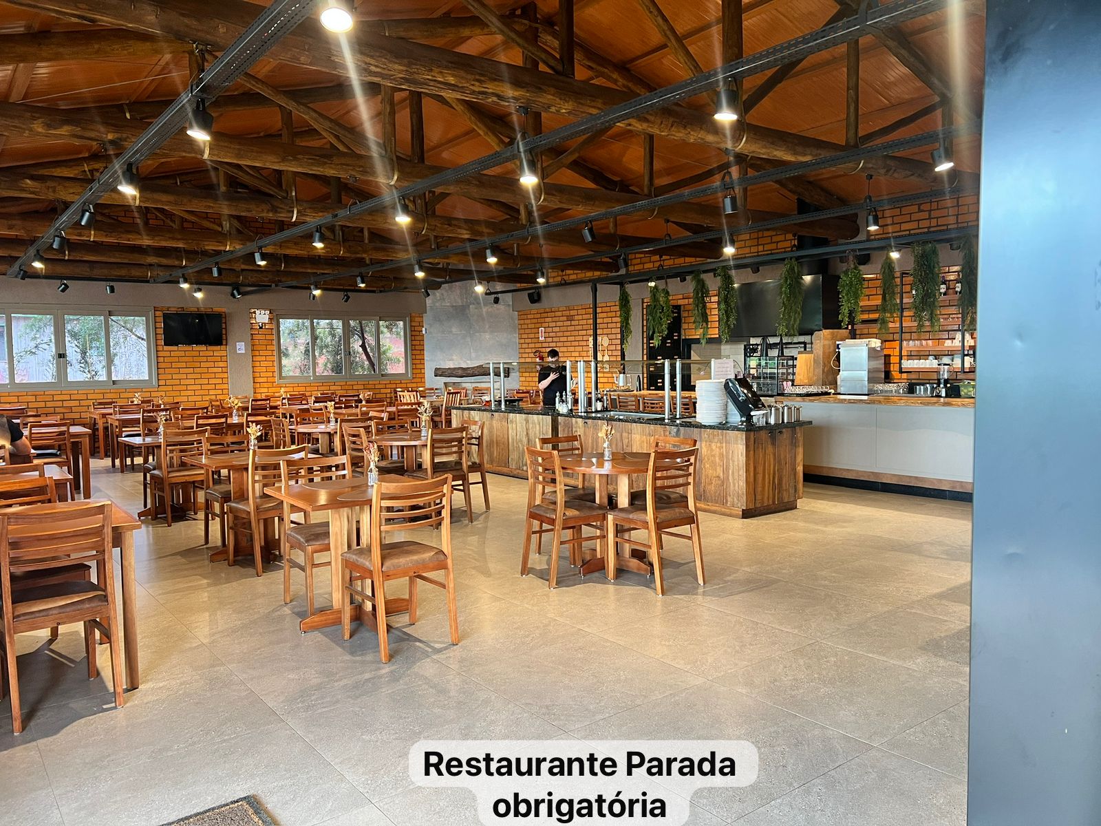 Salão do Restaurante Parada Obrigatória, com mesas, estrutura de madeira e iluminação